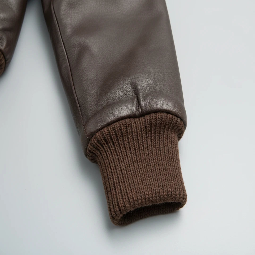 Brown leather jacket with ribbed cuffs on a light gray background