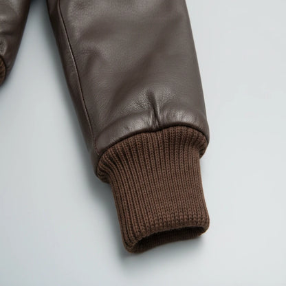 Brown leather jacket with ribbed cuffs on a light gray background